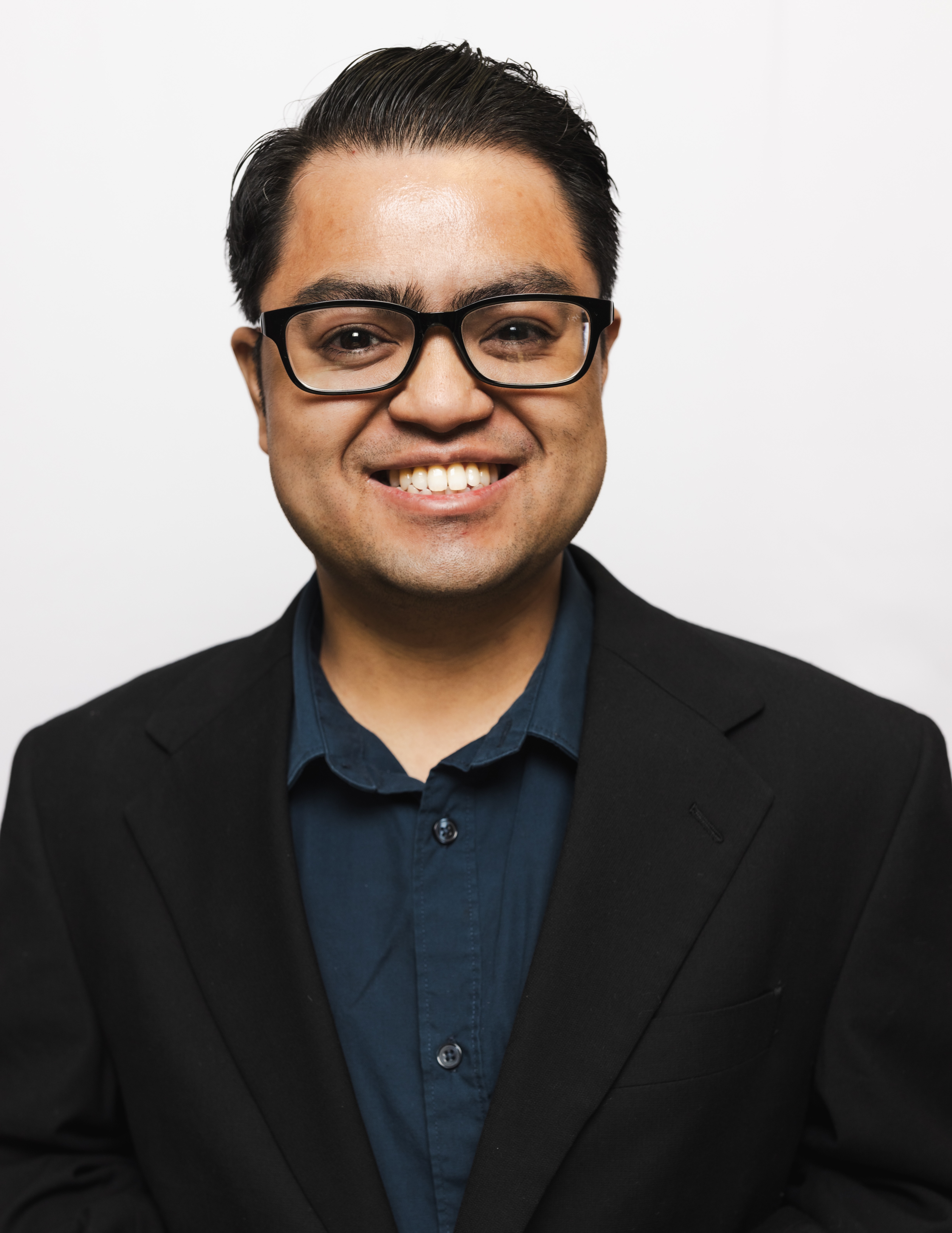 Man in a suit and glasses smiling at the camera