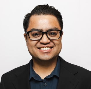 Man in a suit and glasses smiling at the camera