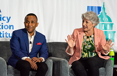 Two experts sitting on chairs talk about public health at the Policy Action Institute event in 2023
