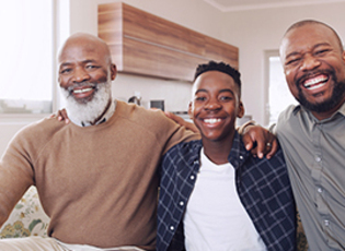 Three generations of men pose with arms on one another's shoulder