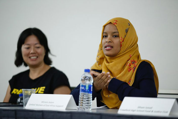 Two women at table, one speaking one smilining
