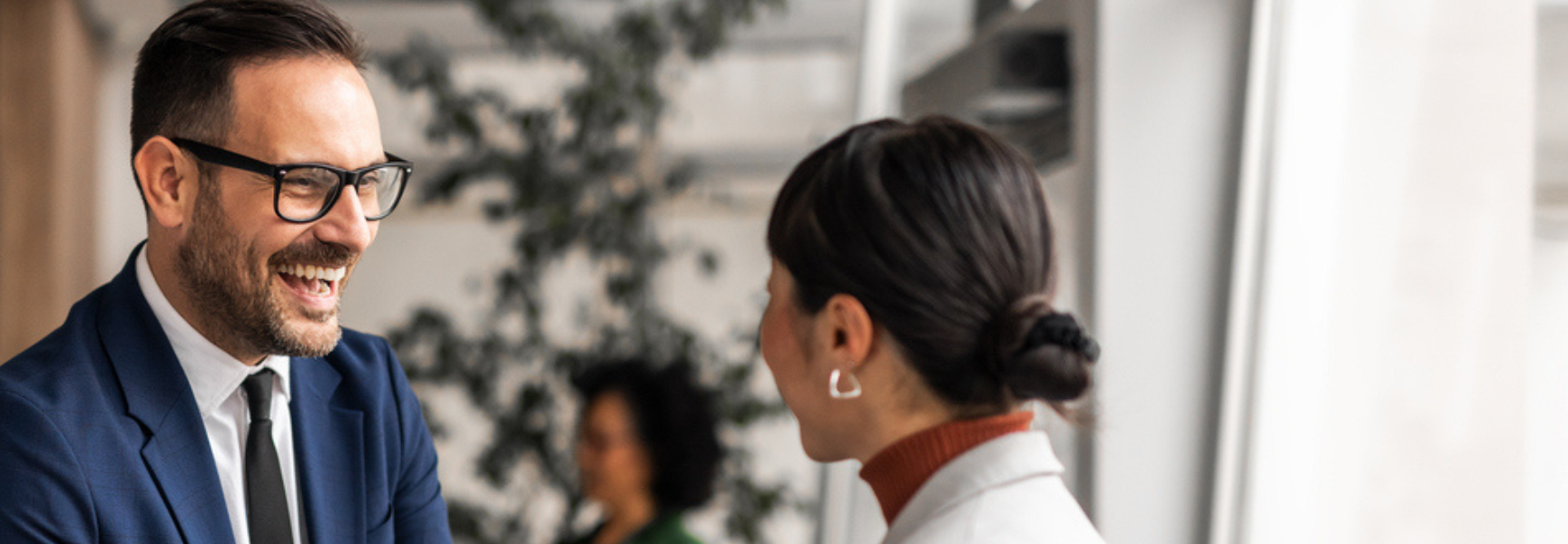 A man and woman shaking hands in business outfits