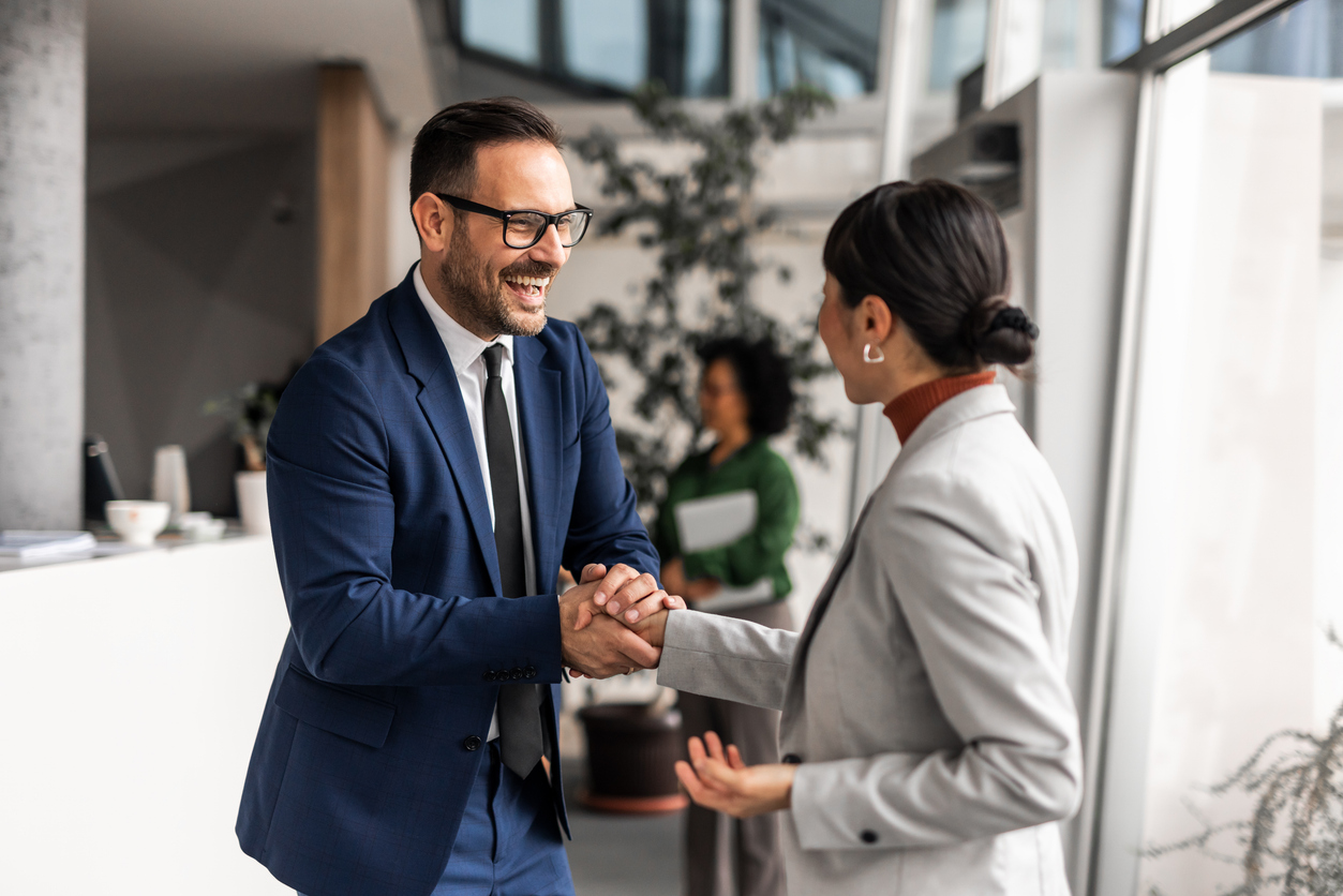A man and woman shaking hands in business outfits