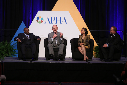 four people seated on stage, APHA logo in background