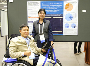 Two presenters giving a poster presentation at the APHA annual meeting, one in a wheelchair