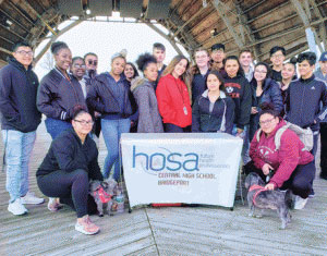 smiling people gathered behind 'hosa' banner