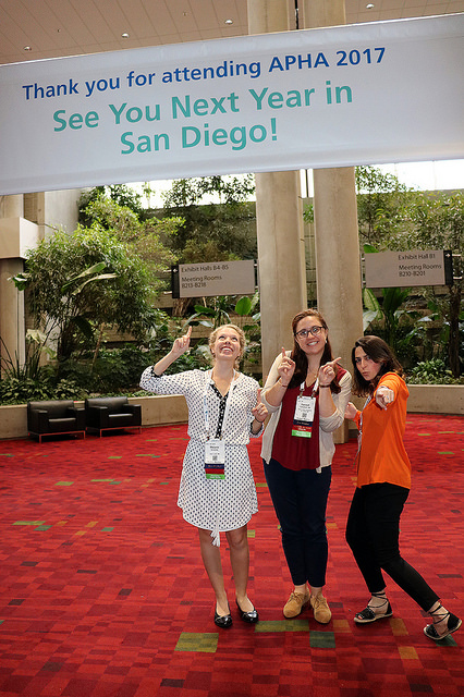 three women pointing at see you next year sign
