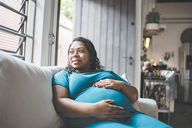 A woman who is pregnant reclines on a sofa