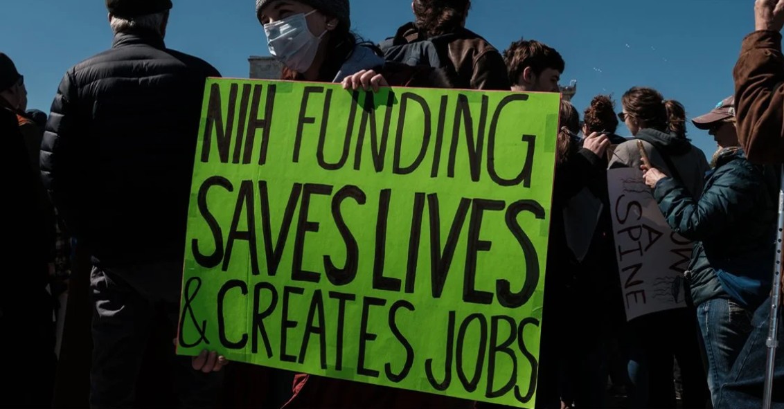 NIH staff protesting with a green sign
