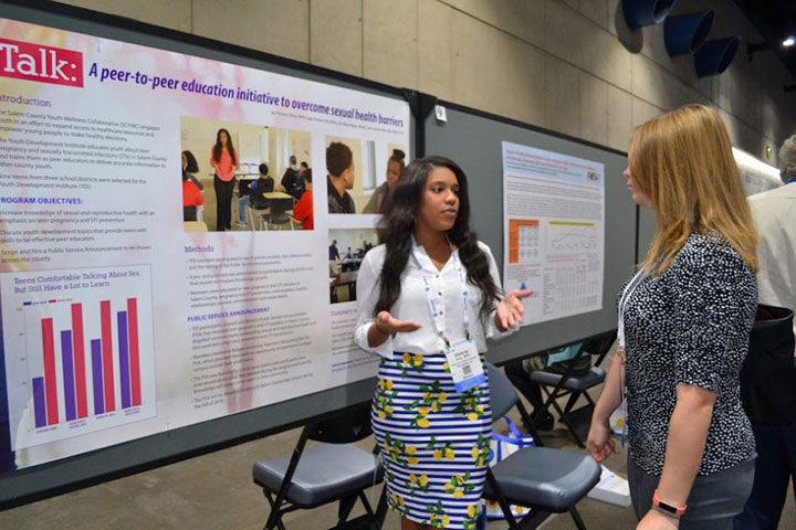 woman discussing poster as second woman looks on