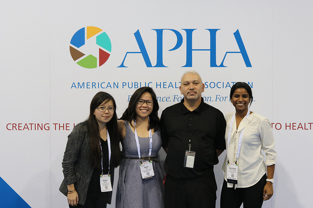 four smiling people in front of APHA logo