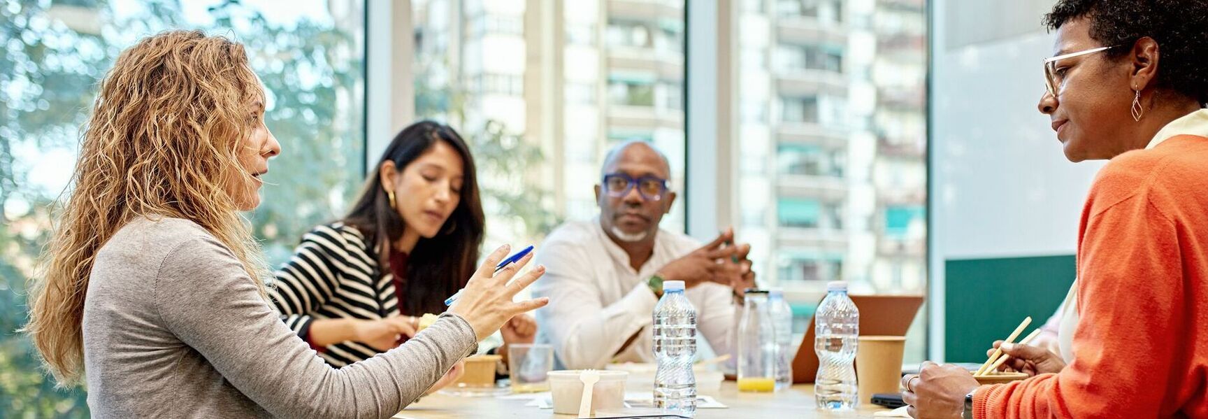Coworkers in 20s and 40s conversing in meeting room stock photo
