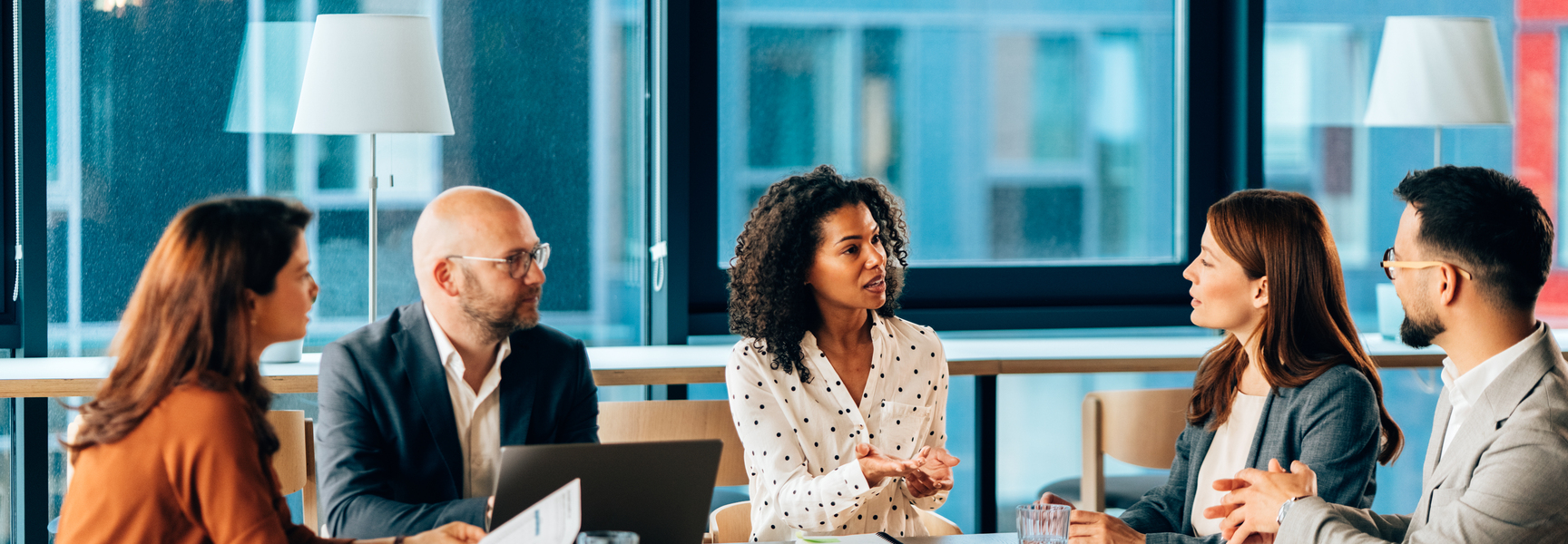 Coworkers in 20s and 40s conversing in meeting room stock photo