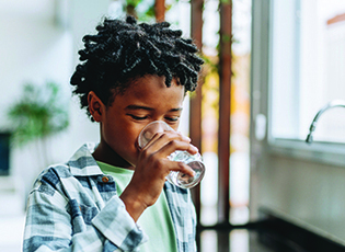 A boy drinks water from a glass