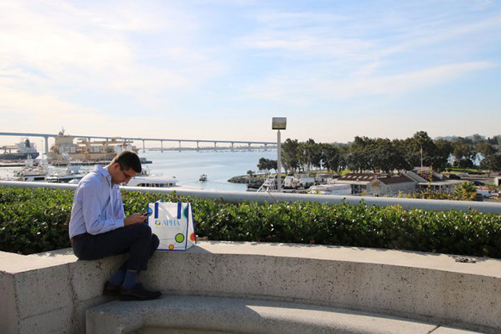 man seated outside with San Diego waterfront in background