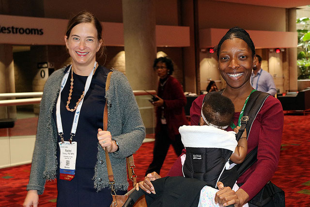 two smiling women walking, one with baby 