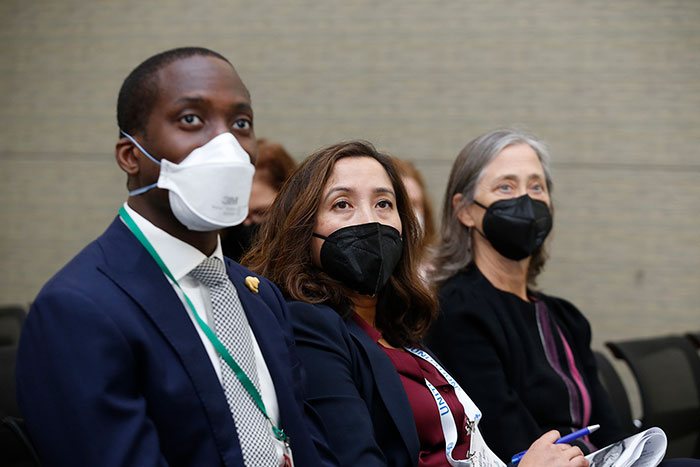 A trio of attendees watch a session presentation. 