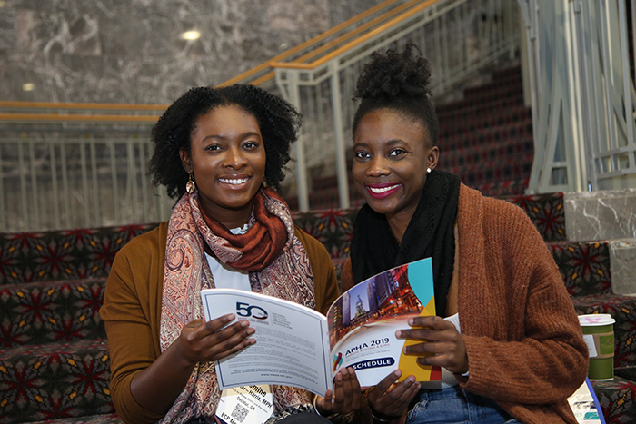 two smiling women check out the Annual Meeting printed program