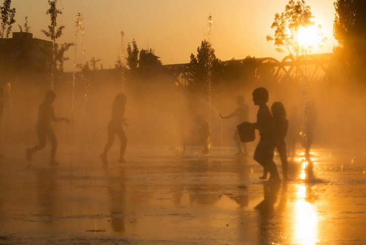 Silhouettes of playful children in a fountain in sunlight