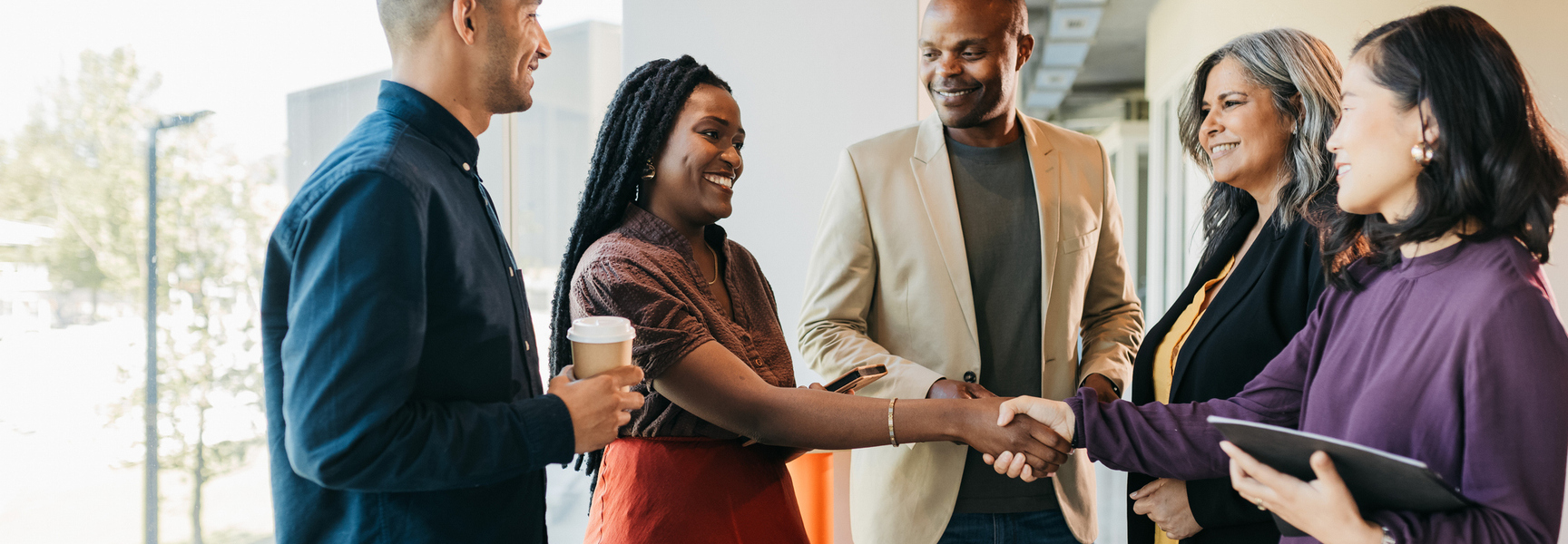 Group of multiracial business partners shaking hands in coworking office space stock photo