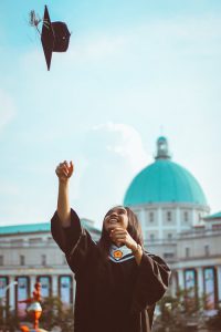 smiling woman throwing graduation cap in air