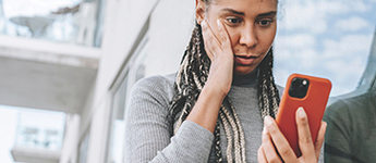 A woman shows concern on her face as she looks at her cellphone